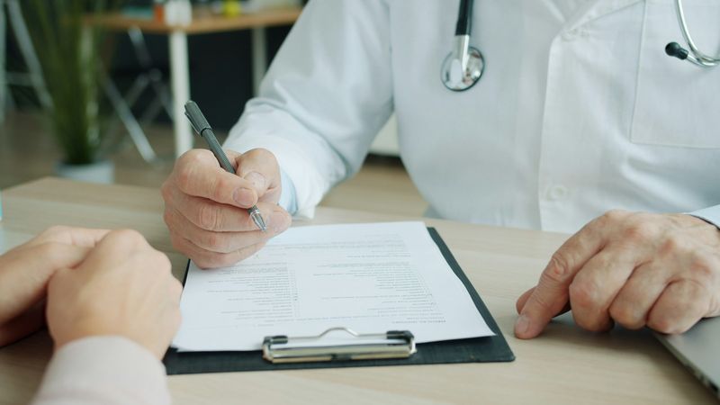 Lekarz wypełnia dokumentację przy biurku podczas wizyty